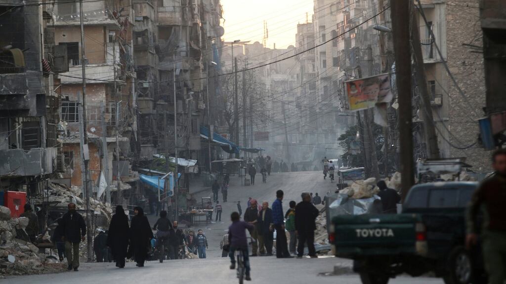 People walk along a street near damaged buildings in Tariq al-Bab neighbourhood of Aleppo, Syria. Photograph: Abdalrhman Ismail/Reuters