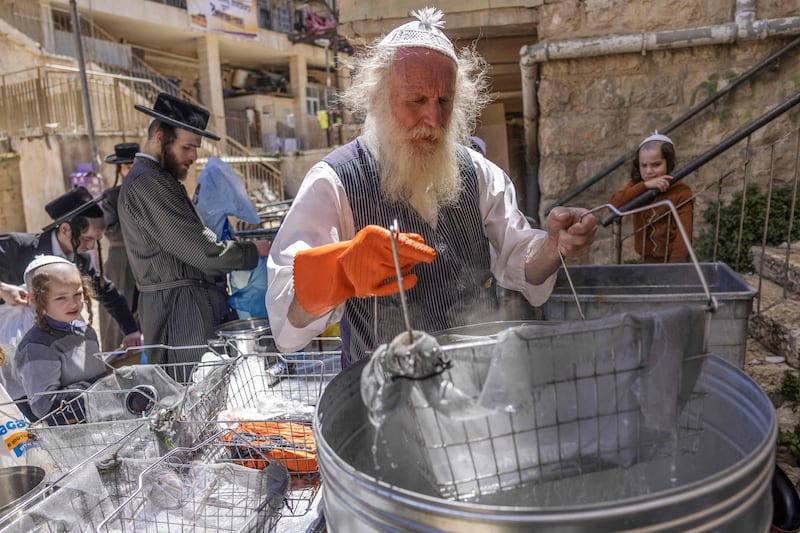 An Ultra-Orthodox Jewish man dips cooking utensils in boiling water to remove traces of chametz in Jerusalem's Mea Shearim neighbourhood. Photograph: Menahem Kahana/AFP/Getty