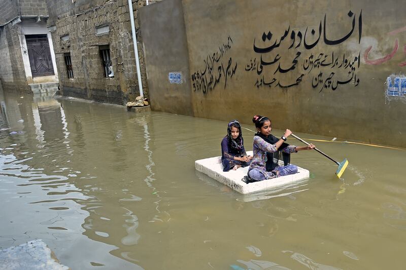 Girls use a temporary raft across a flooded street in a residential area in Karachi. Photograph: Rizwan Tabassum/AFP via Getty Images)