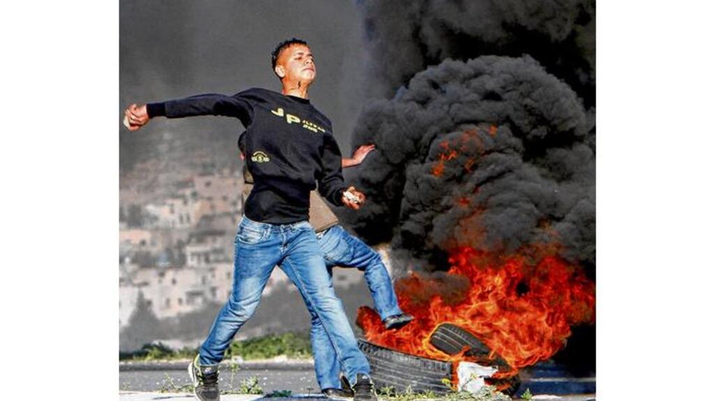 Palestinian youth hurls a stone towards Israeli soldiers during clashes at Hawara checkpoint near the West Bank city of Nablus yesterday. photograph: abed omar qusini