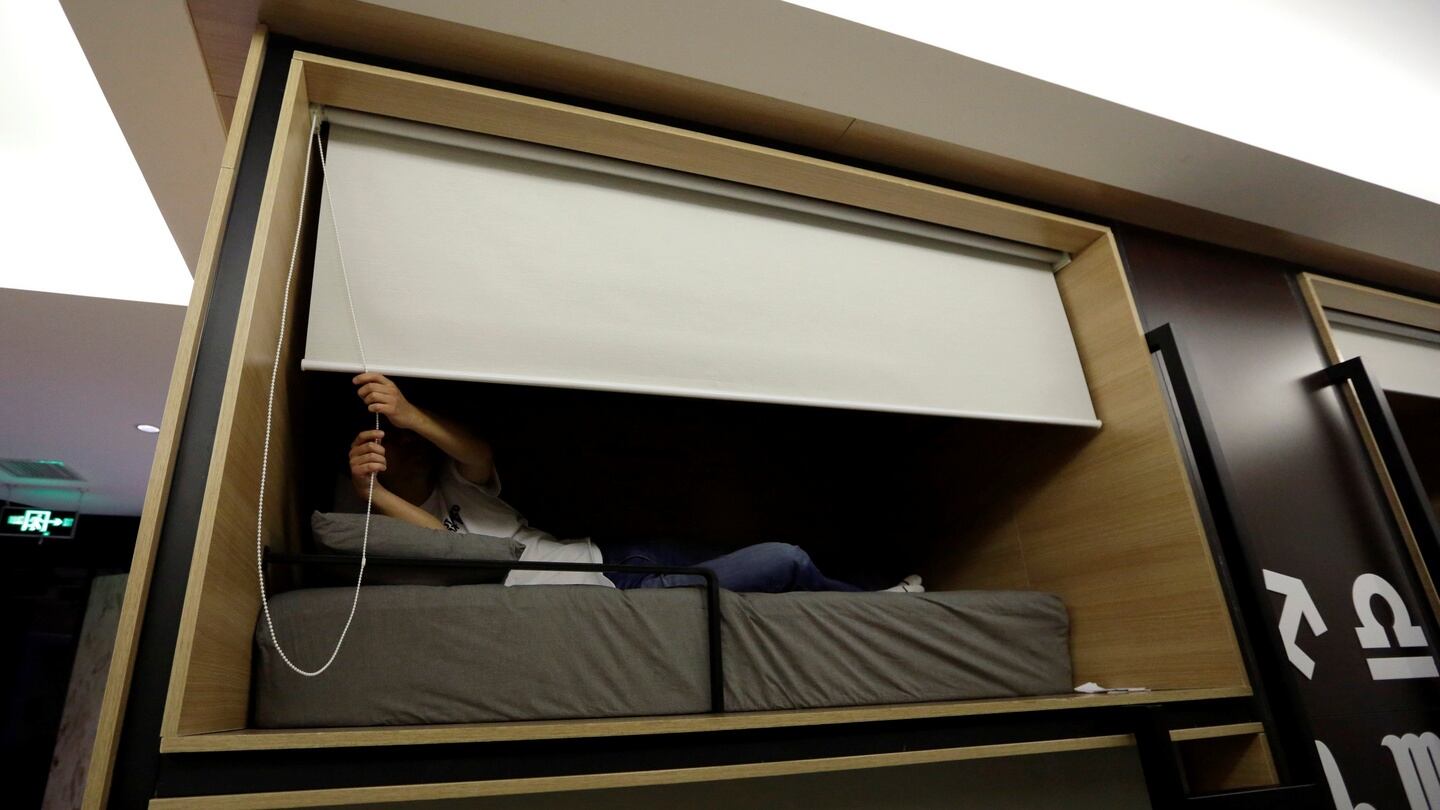 Zhang Shuangjie, an IT engineer at BaishanCloud, drops the curtain as he prepares to sleep around midnight in an individual sleeping quarter in the office. Photograph: Jason Lee/Reuters