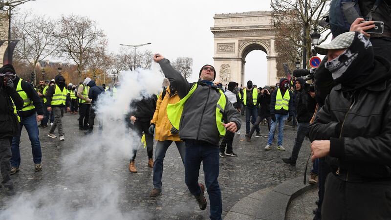 A demonstrator throws a tear gas canister during the demonstration of the yellow vests at the Arc de Triomphe. Photograph:  Jeff J Mitchell/Getty Images