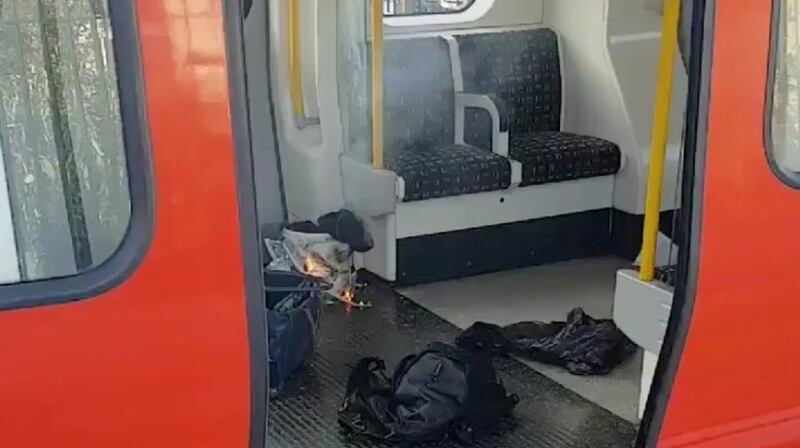 Personal belongings and a bucket with an item on fire inside it are seen on the floor of an underground train carriage at Parsons Green station in West London