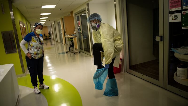 Dr Abhishek Patel (right) puts on personal protective equipment before entering the room of one of his youngest patients in the Children’s Hospital of San Antonio. Photograph: Meridith Kohut/The New York Times