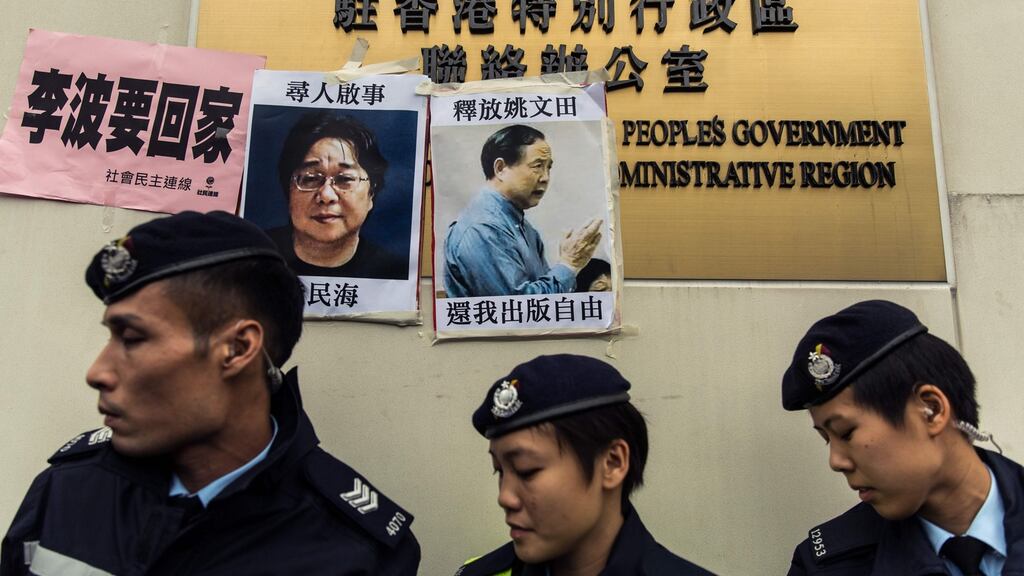 Police walk past a missing person notices for Gui Minhai (left), in Hong Kong in January 2016. He has been taken into custody again in China. Photograph: Anthony Wallace/AFP