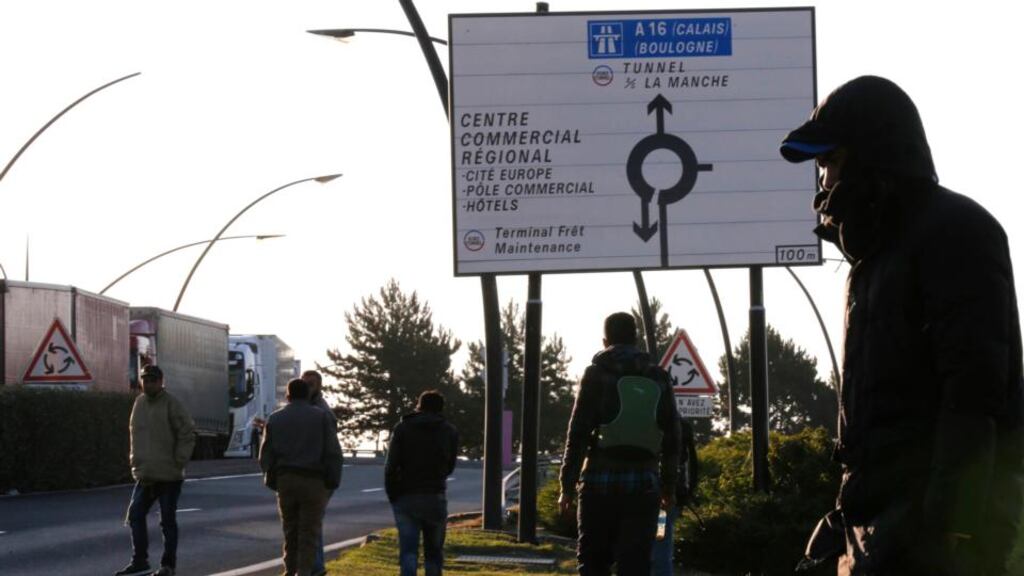 Migrants walk near the road where lorries pass after leaving their hiding spot at the Eurotunnel site in Calais. Photograph: Pascal Rossignol/Reuters