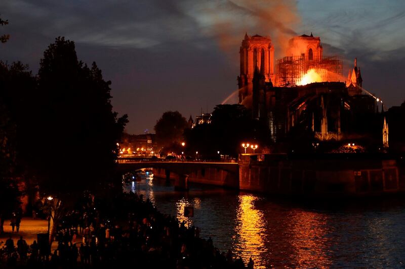 Gathered crowds line the banks of the river Seine will firefighters attept to control the blaze. Photograph: Thomas Samson/AFP/Getty