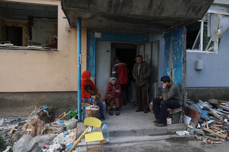 Local residents sit at the entrance of an apartment building destroyed by shelling in the village of Ocheretyne. Photograph: Anatolii Stepanov/AFP via Getty Images