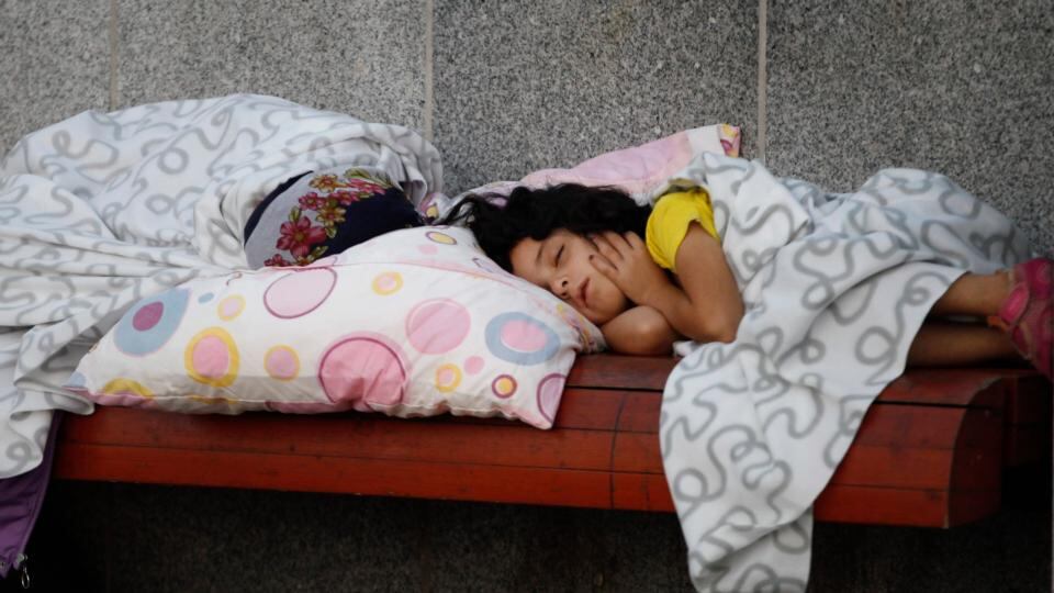 A young girl sleeps on a bench as migrants rest near the Keleti Railway Station in Budapest. Photograph: Petr David Josek/AP
