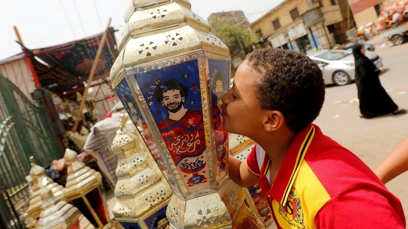 An Egyptian boy kisses the traditional decorative lanterns known as “Fanous” bearing the image Salah, at a market before the beginning of the holy fasting month of Ramadan in Cairo. Photo: Amr Abdallah Dalsh/Reuters