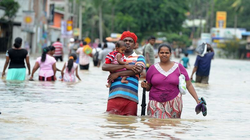 A Sri Lankan couple with their child make their way through floodwaters in the suburb of Kaduwela in capital Colombo. Photograph: Larruwan Wanniarachchila/Getty Images