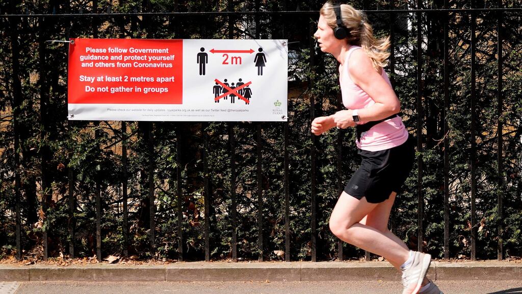 A jogger runs past a sign telling people to adhere to social distancing guidelines, and stay 2m  apart, in London. Photograph: Niklas Halle’n/AFP via Getty Images
