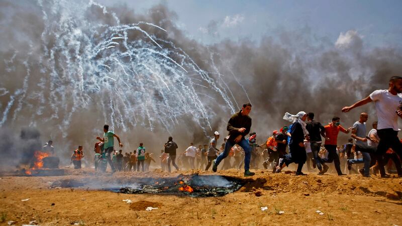 Palestinians run for cover from tear gas during clashes with Israeli security forces near the border between Israel and the Gaza Strip on Monday. Photograph: Mohammed Abed/AFP/Getty Images