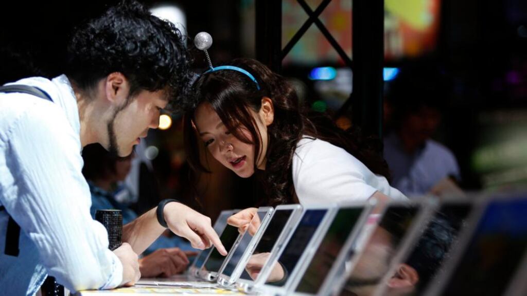 Demonstrators explains new mobile game software on Apple’s iPad to a visitor at Tokyo Game Show 2014. Photograph: Reuters/Yuya Shino