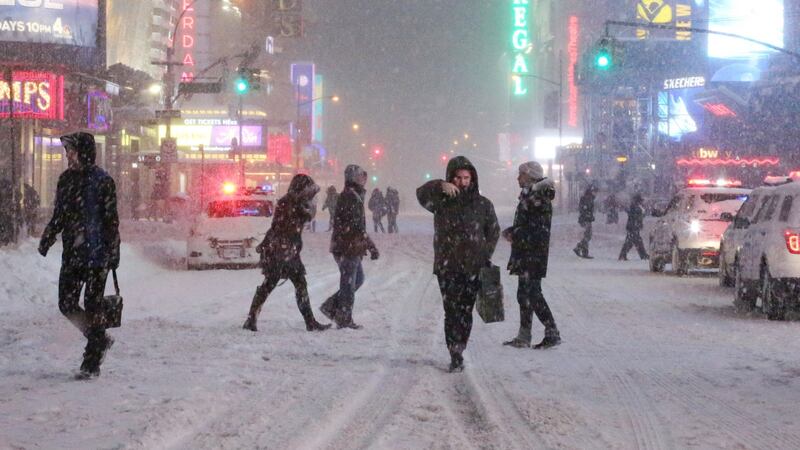Pedestrians walk through the snowy streets near Times Square as all cars but emergency vehicles are banned from driving on the road on Saturday in New York City. Photograph: Yana Paskova/Getty Images
