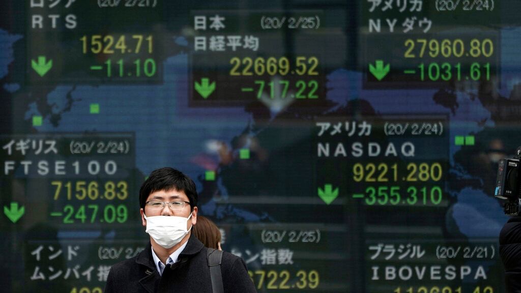 A man stands in front of an electronic stock board showing Japan’s Nikkei 225 index and other city’s index at a securities firm in Tokyo