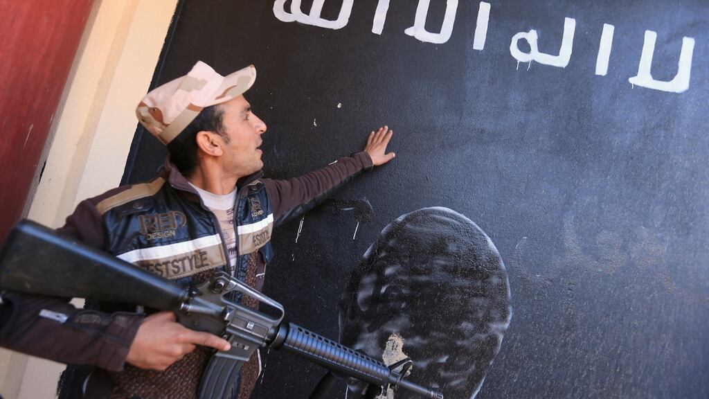 An Iraqi soldier looks at a wall painted in the colours of the black flag commonly used by Isis militants, in the village of Argoob, Iraq, on Friday. Photograph: Ari Jalal/Reuters