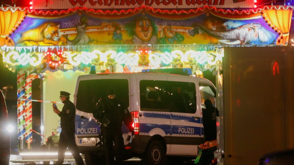 A policeman with a fire extinguisher over his shoulder walks next to a police car in front of a Christmas market stall in Potsdam, after it was evacuated by policeon Friday. Photograph: Felipe Turela/EPA