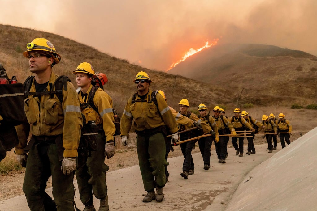 LA fires: Fire crews walk as they battle the Kenneth fire in the West Hills section of Los Angeles. Photograph: Ethan Swope/AP