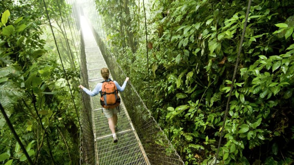 A young woman hikes along a hanging bridge near Arenal Volcano National Park in Costa Rica.