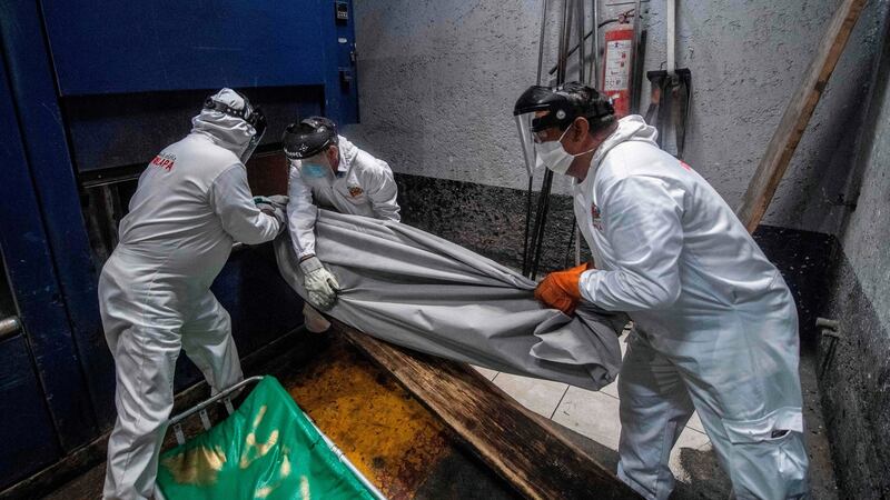 Employees put a body bag with the remains of a victim of Covid-19 in an oven at a crematorium in Mexico City. Photograph: Pedro Pardo/AFP via Getty Images