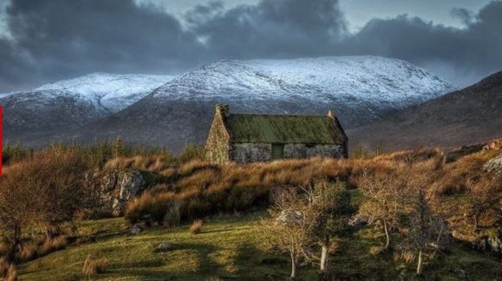 A cottage in Connemara, Co Galway with snow topped hills in the background. Photograph: Trevor Dubber