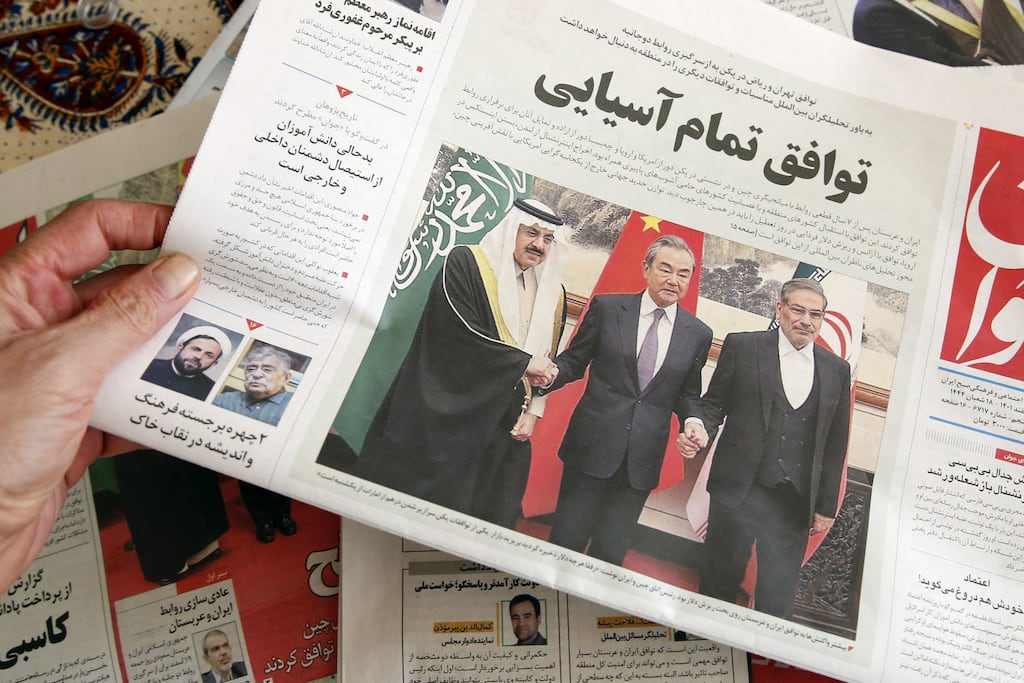 A man in Tehran holds a local newspaper reporting on its front page the China-brokered deal between Iran and Saudi Arabia to restore ties, signed in Beijing.(Photo by Atta Kenare / AFP) (