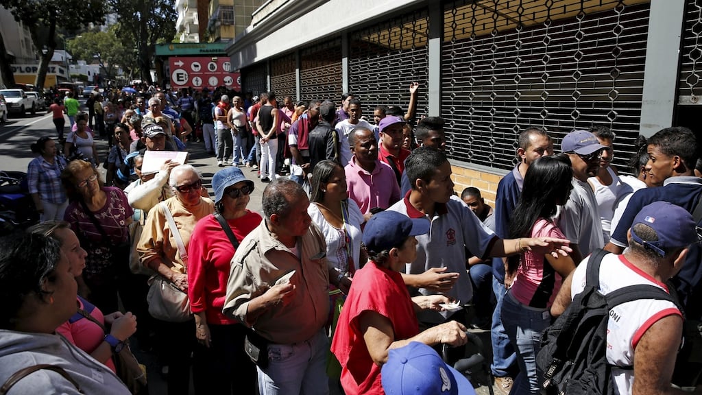 People queue to try to buy corn flour and rice, outside a supermarket in Caracas after Venezuela’s socialist government decreed an “economic emergency”. Photograph: Carlos Garcia Rawlins/Reuters