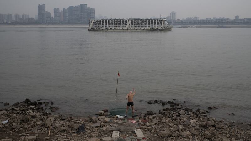 A man warms up for a swim in the Yangtze as a cargo carrier laden with cars passed by in Wuhan in early January. Photograph: Gilles Sabrie/The NewYork Times