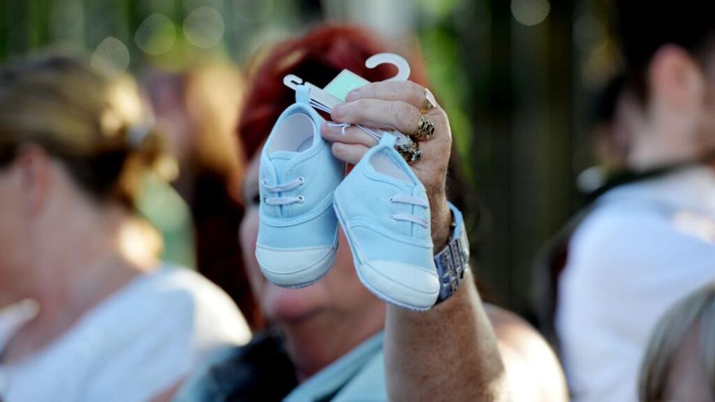 An infant’s shoes are held up at a march of 300 people from the Department of Children and Youth Affairs on Mespil Road to Government Buildings to protest about the death of babies at the Tuam mother-and-baby home. Photograph: Alan Betson