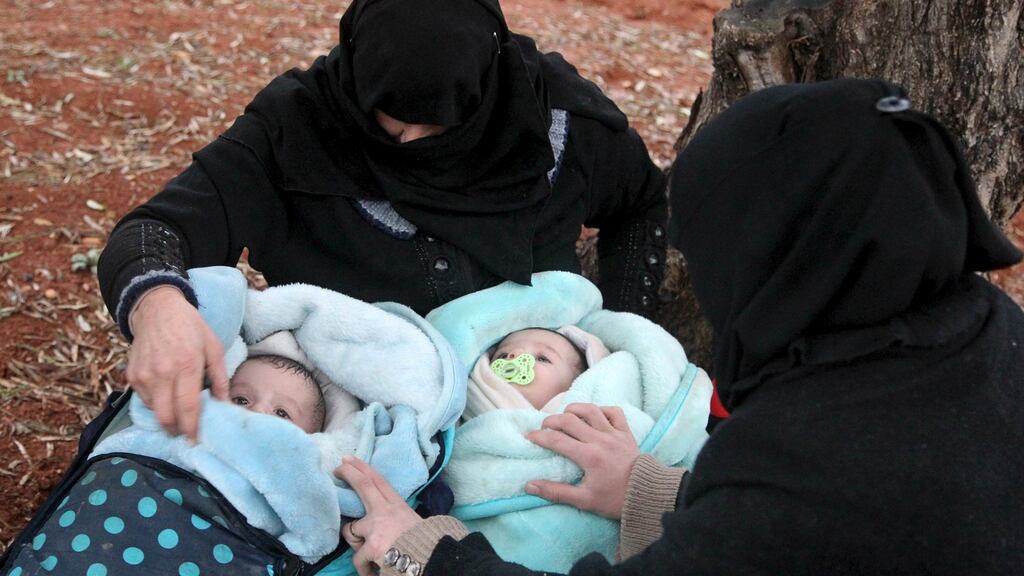 Displaced women, who fled the violence from Islamic State-controlled area of al-Bab, look at the faces of baby twins as they waited in the Syrian village of Akda to cross into Turkey on Saturday. Photograph: Abdalrhman Ismail/Reuters