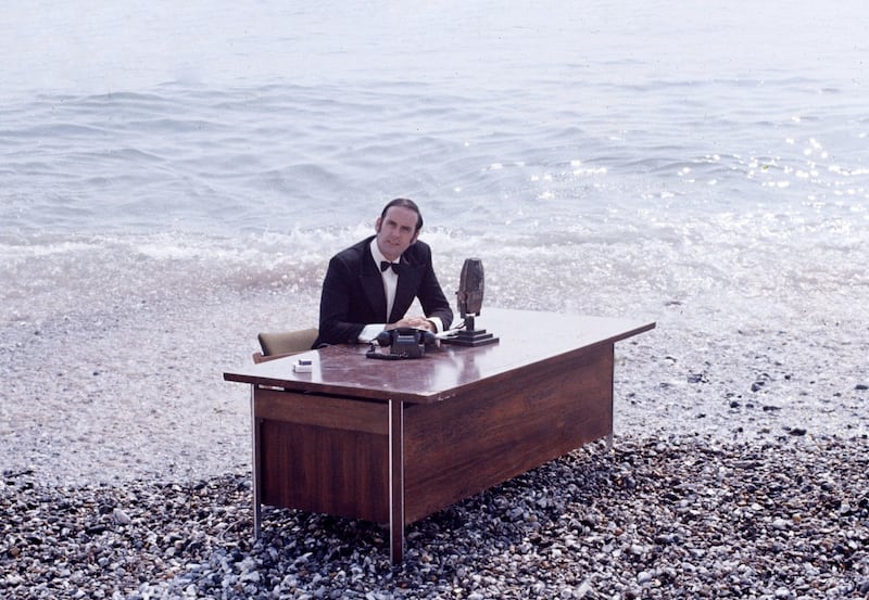 EMBARGOED TO 0001 SATURDAY OCTOBER 5ONE USE ONLYFor use in UK, Ireland or Benelux countries only Undated BBC handout photo of John Cleese sitting at a desk on the beach from 'now for something completely different' sketch. An archive of unearthed Monty Python material has been released to celebrate 50 years of the comedy troupe. PA Photo. Issue date: Saturday October 5, 2019. The six-strong group first appeared on the BBC on October 5 1969 and went on to have global success with their often surreal comedy. Photos and documents revealing the early days of Python have been discovered and restored. See PA story SHOWBIZ Python. Photo credit should read: Python (Monty) Pictures Limited/BBC/PA WireNOTE TO EDITORS: Not for use more than 21 days after issue. You may use this picture without charge only for the purpose of publicising or reporting on current BBC programming, personnel or other BBC output or activity within 21 days of issue. Any use after that time MUST be cleared through BBC Picture Publicity. Please credit the image to the BBC and any named photographer or independent programme maker, as described in the caption.