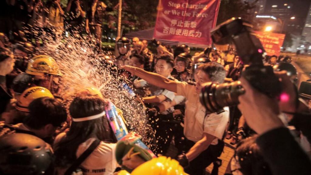 A police officer sprays pepper spray at demonstrators during a protest outside the central government offices in the Admiralty district of Hong Kong. Photograph: Billy HC Kwok/Bloomberg
