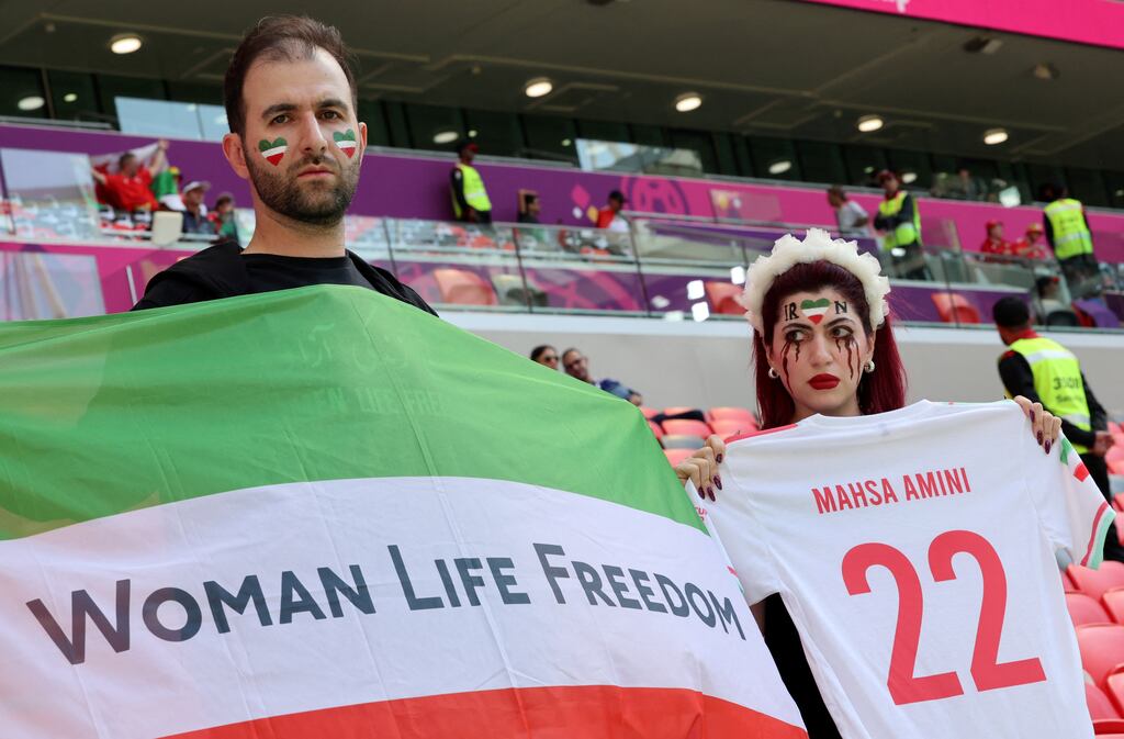 Iran soccer supporters hold up a flag and jersey to protest at the death of Mahsa Amini while in the custody of the Tehran morality police in September. Almost 500 protesters are reported to have died in Iran since mid-September. Photograph: Giuseppe Cacace/AFP via Getty Images