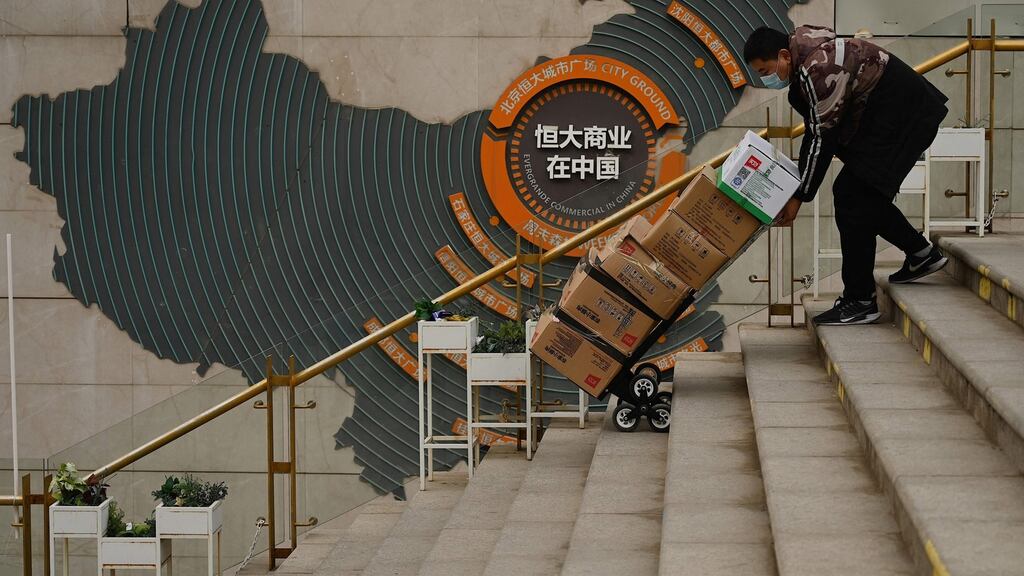 A worker pusher a cart in front of a sign showing Evergrande Group’s China operation at a housing complex by the property developer in Beijing. Photograph: Noel Celis/AFP via Getty Images