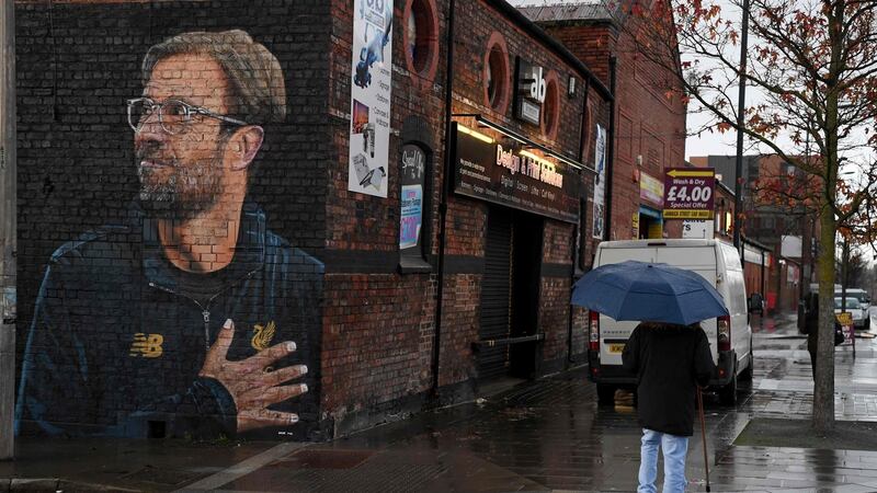 A woman walks past a recently created mural of Liverpool’s German manager Jurgen Klopp by street artist “Akse” in Liverpool. Photo: Paul Ellis/Getty Images