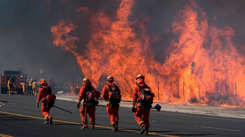 Firefighters prepare to put out flames on the road leading to the Ronald Reagan library  in Simi Valley, California, on Wednesday. Photograph: Mark Ralston/AFP via Getty Images