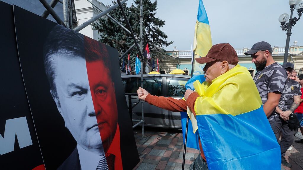 A protester   gestures at a placard with combo portrait picturing faces of the President Poroshenko and former president Yanukovich with a slogan ‘No to elections with Yanukovich law’ during their rally near the Parliament building in Kiev, Ukraine. Photograph: EPA