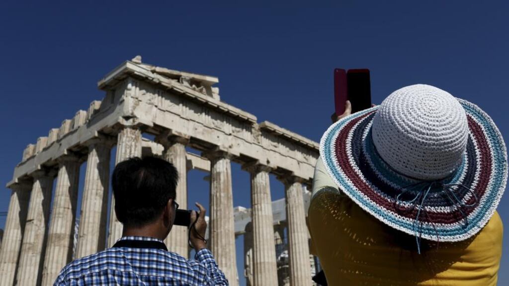 Visitors take pictures in front of the Parthenon temple atop the Acropolis hill in Athens. Photograph: Kostas Tsironis/Reuters