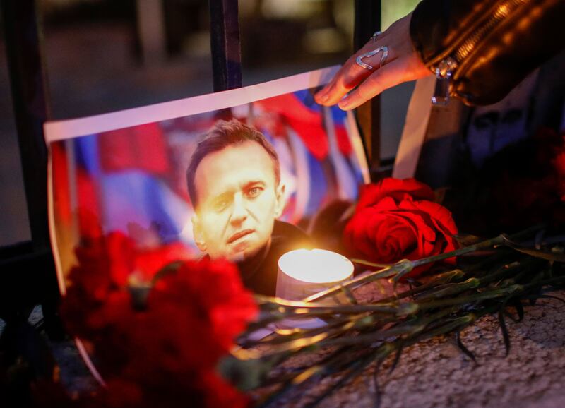 A woman lights a candle during a rally following the death of Alexei Navalny, outside the Russian Embassy in Tbilisi, Georgia. Photograph: David Mdzinarishvili/EPA