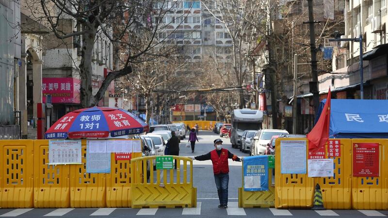 A volunteer standing at a barrier set up to prevent people from entering or leaving a community in Wuhan. Photograph: STR/AFP via Getty