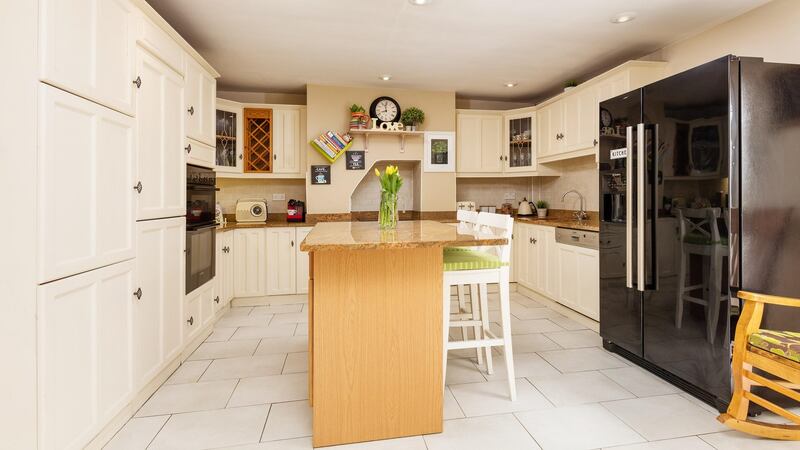The kitchen/breakfastroom is in shades of white, with a ceramic tiled floor and a dappled mustard polished granite topping the centre isle and worktops