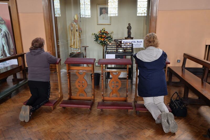 Two women pray in front of the  statue of  St Roch. Photograph: Alan Betson/The Irish Times