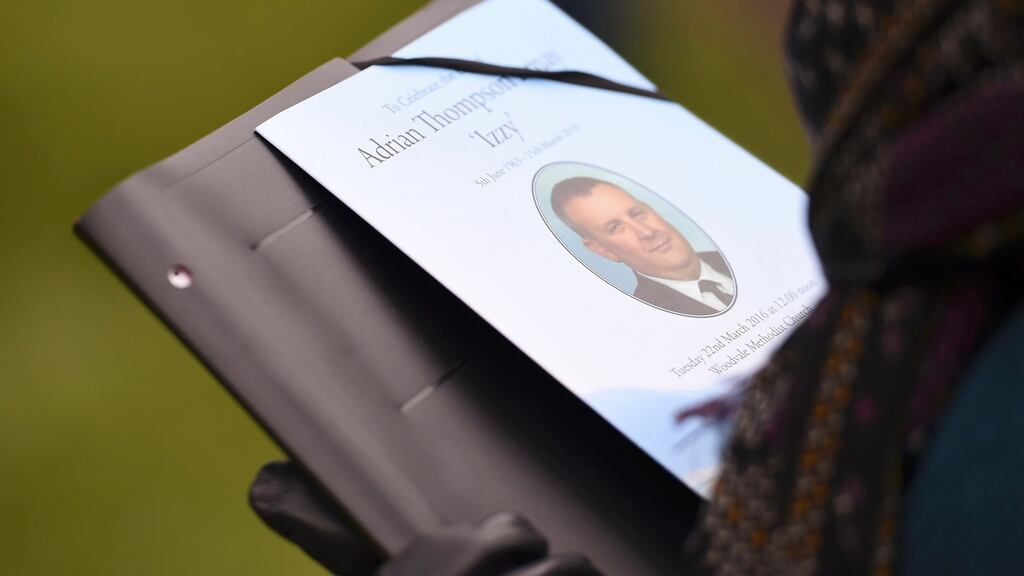 A mourner holds a printed tribute at the funeral service for prison officer Adrian Ismay, at Woodvale Methodist Church in Belfast. Photograph: Clodagh Kilcoyne/Reuters