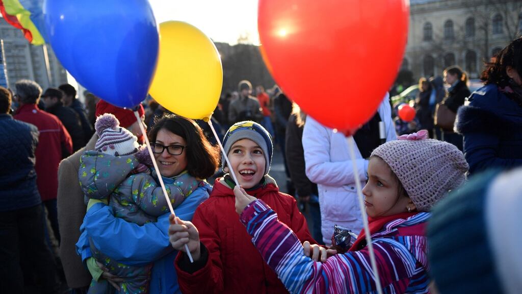 Children hold balloons in the colours of the Romanian flag as people protest against the government’s contentious corruption decree in Bucharest, Romania. Photograph: Daniel Mihailescu/AFP/Getty Images