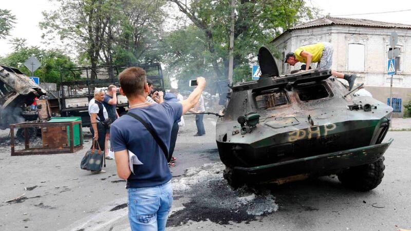 Local residents look at destroyed vehicles at the site of fighting in the eastern Ukrainian port city of Mariupol yesterday. Ukrainian government forces reclaimed Mariupol from pro-Russian separatists in heavy fighting. Photograph: Shamil Zhumatov/Reuters