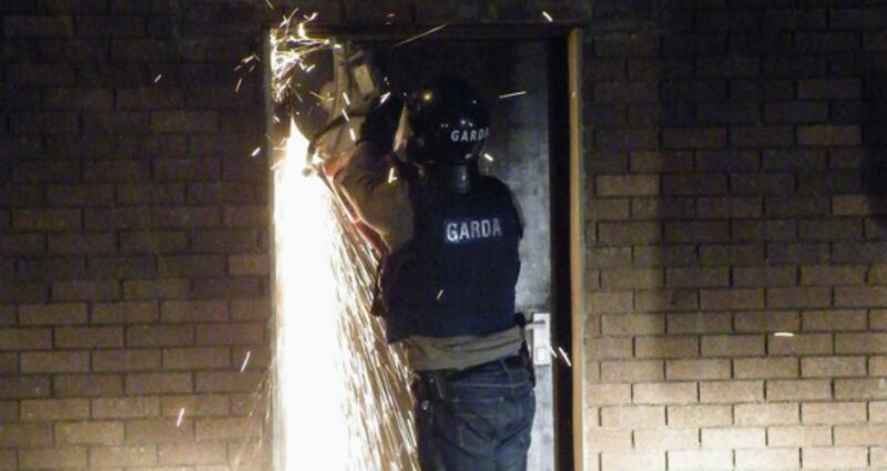 A garda saws through a door at a cannabis growhouse in Tralee early today. Photograph: Garda handout