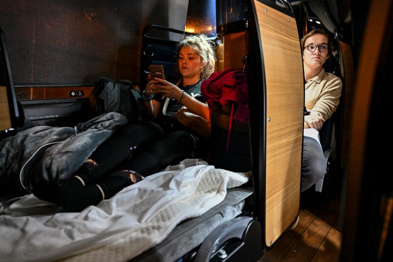 Tyler Zupic, left, stretches her legs as she rides the Napaway sleeper coach during an overnight trip from Washington, D.C., to Nashville, Tenn., Oct. 14, 2022. Startup travel companies are hoping more Americans will embrace the concept of sleeper and luxury coaches, but don’t dare call them buses. (Kenny Holston/The New York Times)