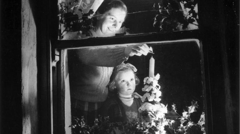A young girl watches her mother light a candle in their window c1955. Photograph: Three Lions/Getty Images