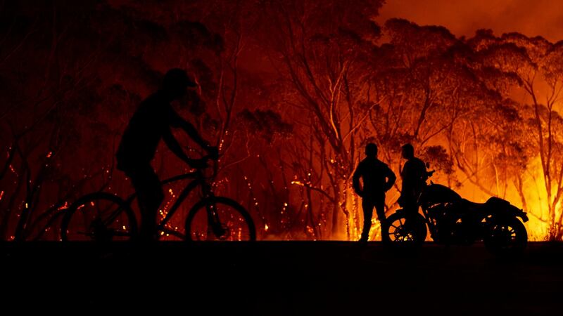 Residents look on as flames burn through bush in Lake Tabourie, Australia. Photograph: Brett Hemmings/Getty Images
